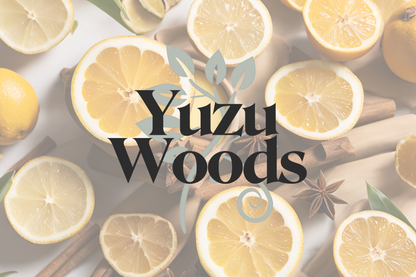 The image is a circular icon or label featuring the text "Yuzu Woods" in bold, handwritten-style font. The background consists of a flat-lay arrangement of sliced lemons, whole lemons, cinnamon sticks, and star anise, giving a fresh, citrusy, and warm visual. The text is overlaid in the center with a transparent circle, creating a clean and minimal look. The overall aesthetic suggests a blend of citrus and spice, consistent with the product’s name and scent profile.